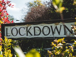 Street sign amongst trees & bushes name with "LOCKDOWN" as street name