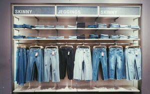 Retail window front with various skinny jeans in various colours on hangers